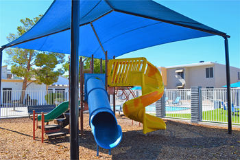 a playground with a blue umbrella and a slide